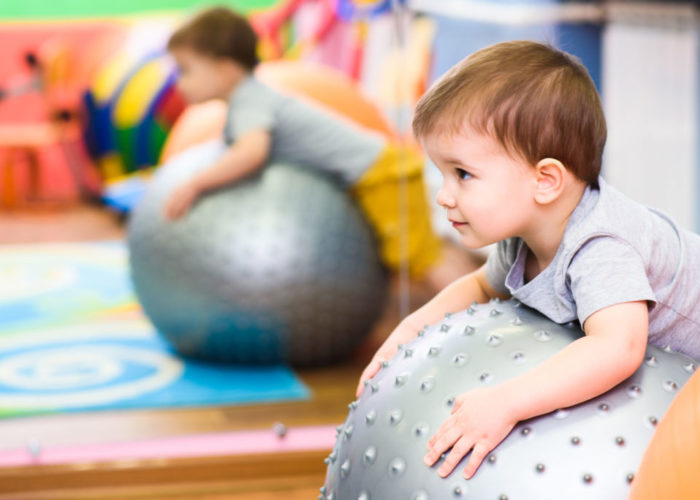 little baby plays with a fitball in the gym