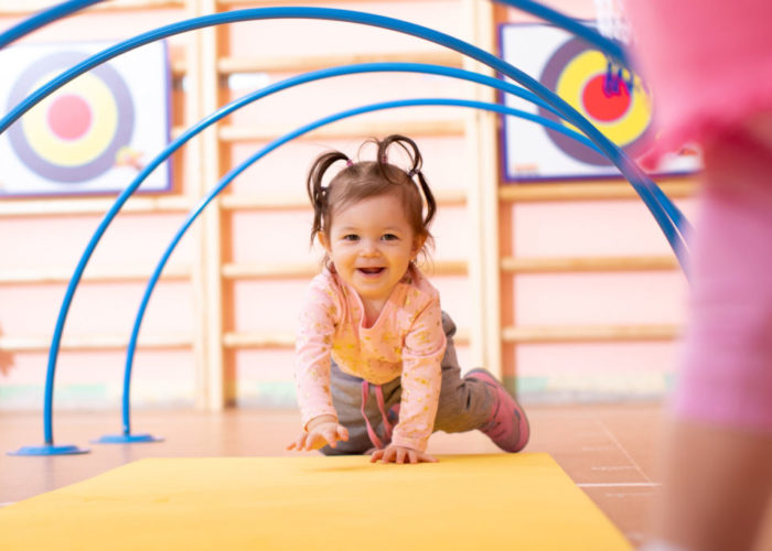 Baby crawling on floor in gym class. Lifestyle concept of children activity.