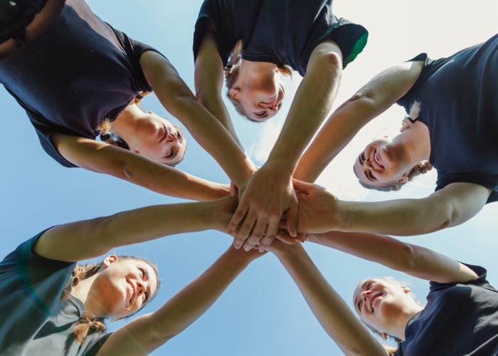smiling-women-putting-hands-together smiling-women-putting-hands-together